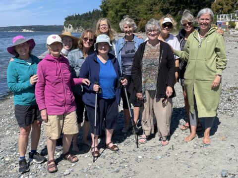 11 smiling white women standing on the beach