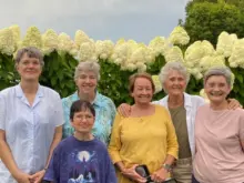 6 smiling white women in front of tall white hydrangeas