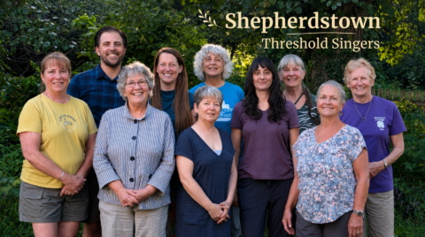 9 smiling women and a man, standing outside